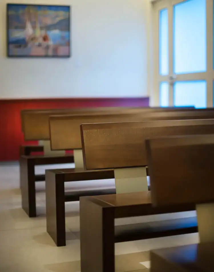 CPL-Salles-Bigot-4 Rangées de bancs en bois dans une salle de cérémonie, avec porte vitrée et tableau en arrière-plan