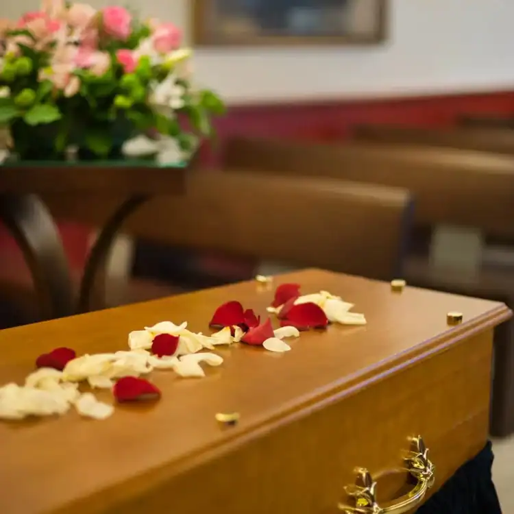 CPL-image-deroulement-de-la-ceremonie Cercueil en bois orné de pétales de roses rouges et blanches, symbole d’hommage et de recueillement lors d’une cérémonie