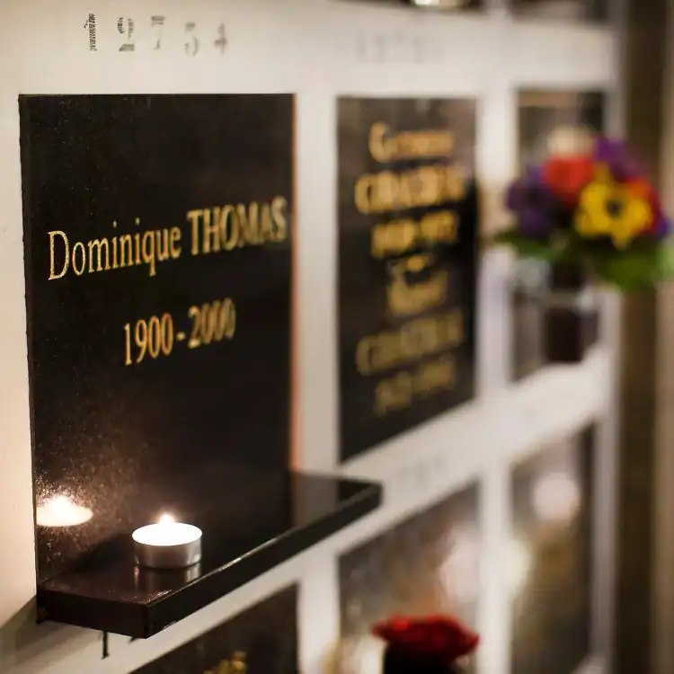 CPL-image-le-columbarium Espace cinéraire avec plaques commémoratives personnalisées, bougie et fleurs, offrant un lieu intime et respectueux pour se recueillir