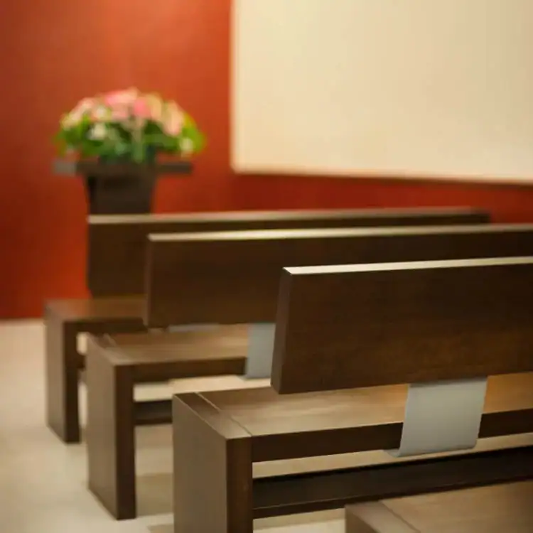 CPL-image-remise-de-lurne Bancs en bois disposés dans une salle de cérémonie, offrant un espace sobre et confortable pour les proches lors des hommages